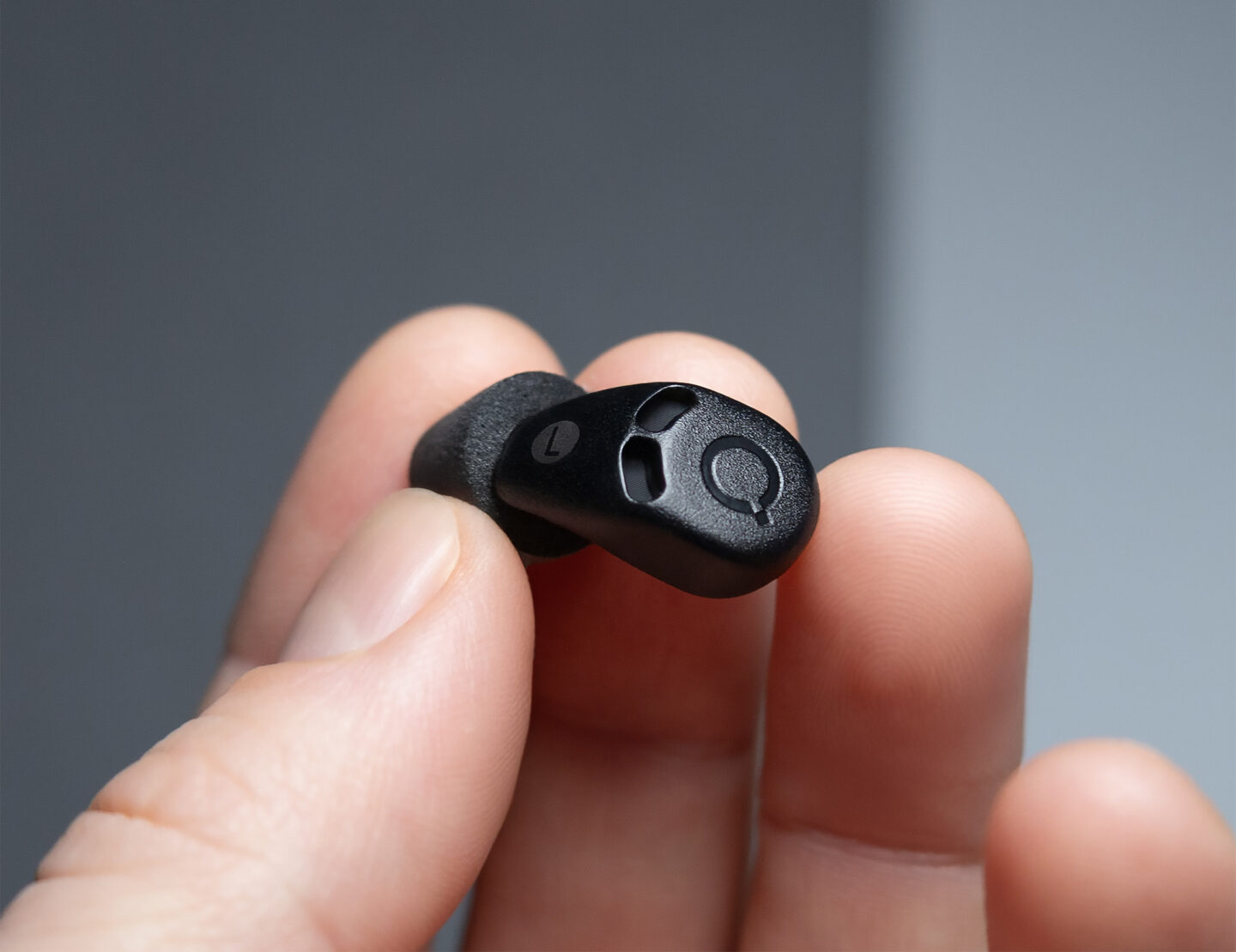 Hand holding a QuietOn sleep earbud designed to block snoring and ambient noise for better rest