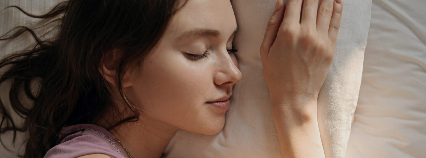 Woman sleeping peacefully with QuietOn 4 active noise-canceling earbuds, blocking snoring and low-frequency noises for better sleep. No Bluetooth, no app, no hassle—just simple, effective noise cancellation