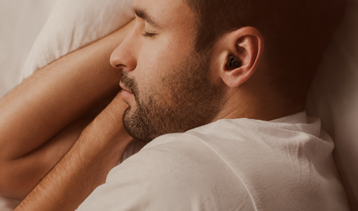Man sleeping peacefully wearing QuietOn 4 sleep earbuds for noise blocking and better sleep