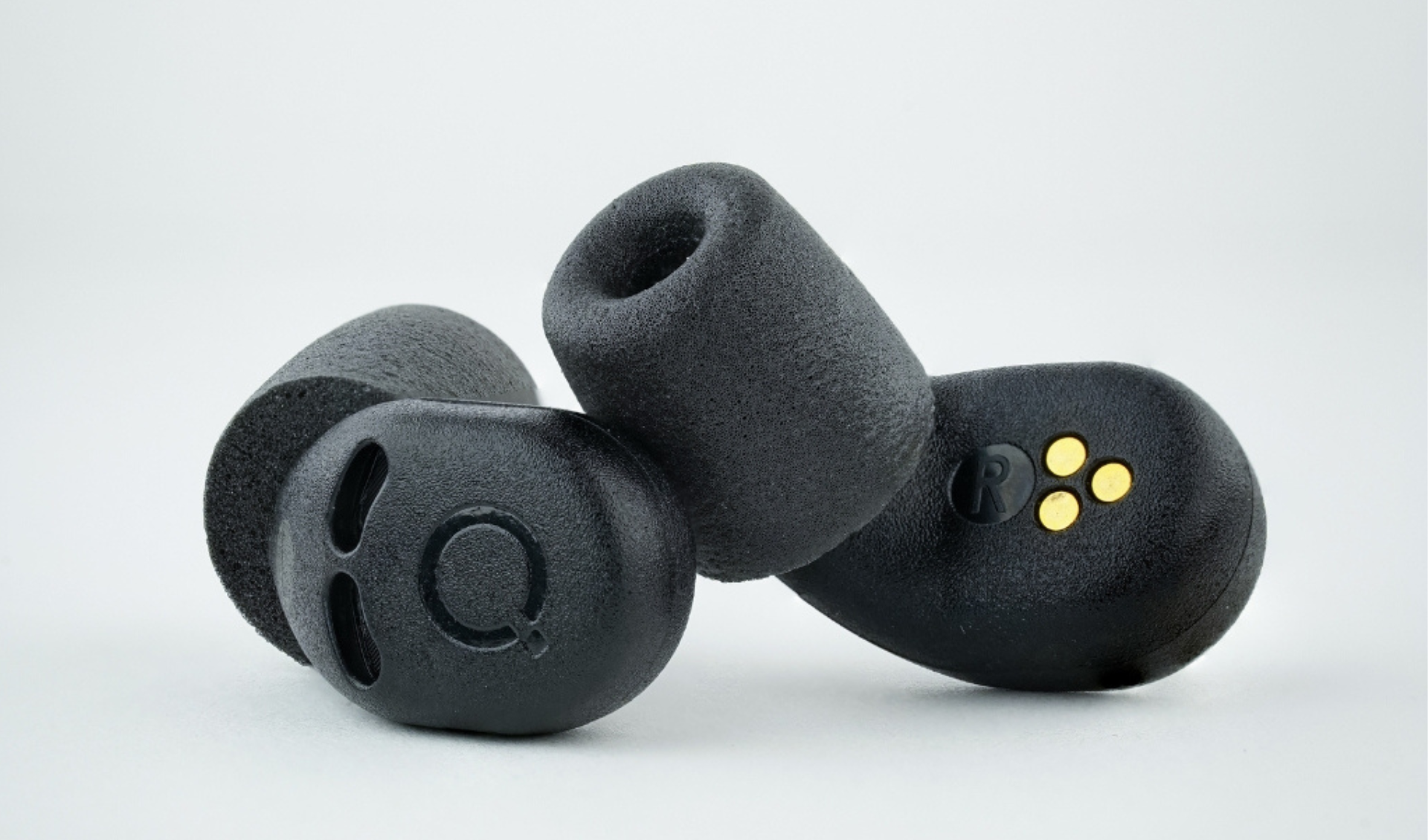 QuietOn 4 sleep earbuds close-up showing soft foam ear tips, QuietOn logo, and gold charging contacts on right earbud